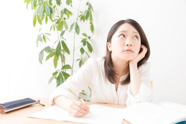 Genç Asyalı kadın evde ders çalışıyor.