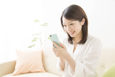 Beyaz üzerine izole edilmiş akıllı telefon kullanan güzel Asyalı bir kadının portresi.