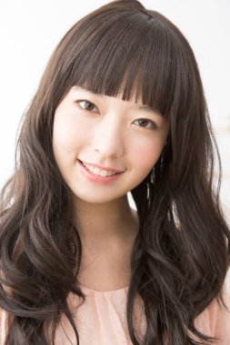 Asyalı genç kadın gülümsüyor ve kameraya bakıyor.