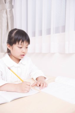 Küçük Asyalı kız ödevini yapıyor. 