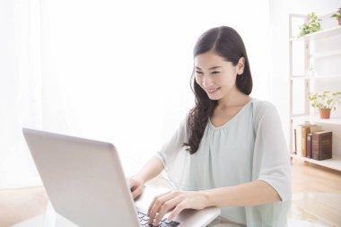 Genç kadın ofiste dizüstü bilgisayar kullanıyor.