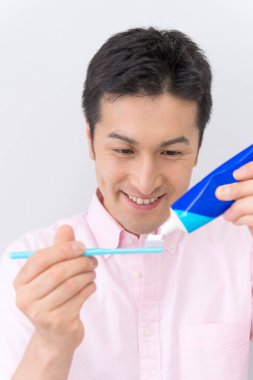 Genç Asyalı adam diş temizliyor.