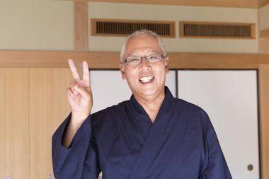 senior man in kimono showing  victory  sign