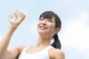 Yaz parkında koşu yaparken su içen güzel Japon kadın. 