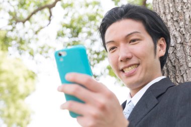 İş adamı parkta cep telefonu kullanıyor.