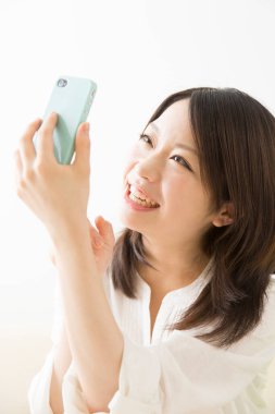 Beyaz üzerine izole edilmiş akıllı telefon kullanan güzel Asyalı bir kadının portresi.