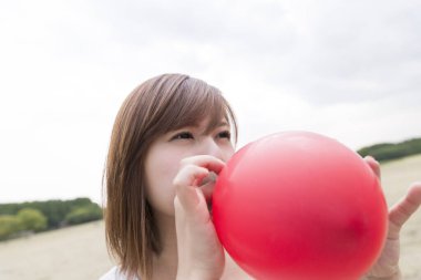Balon şişiren Asyalı kadın