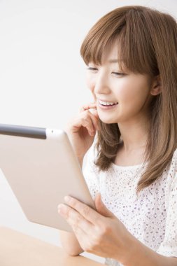 Genç Asyalı kadın dijital tablet kullanıyor.