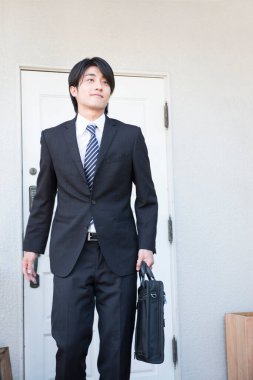 Ofisinde evrak çantası olan Asyalı bir adam. 