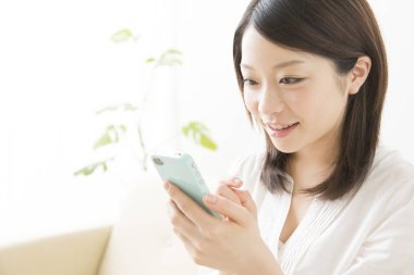 Beyaz üzerine izole edilmiş akıllı telefon kullanan güzel Asyalı bir kadının portresi.