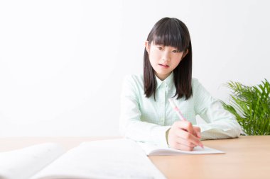 Asyalı öğrenci sınıfta yazıyor. 