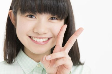 Beyaz arka planda V işareti gösteren Asyalı genç bir kız. 