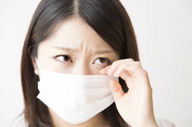 Soluk maskeli hasta bir Asyalı kadının portresi beyaza izole edilmiş.