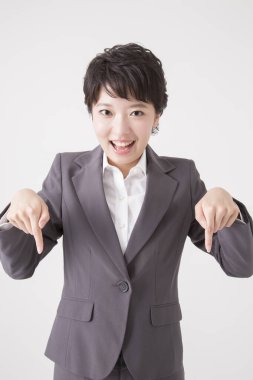 Genç iş kadını gri arkaplanı işaret ediyor