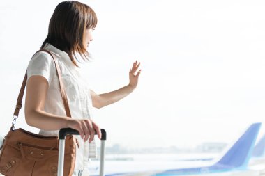 Havaalanı terminalinde bavullu güzel bir Japon kadın.