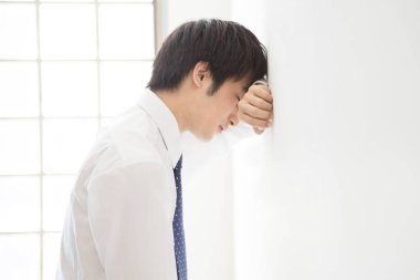 İş adamı düşünüyor ve duvara yaslanıyor 