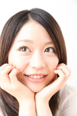 Beyaz arka planda gülümseyen genç Asyalı kadın.