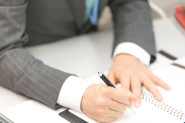 İşadamı spiral deftere notlar yazıyor.