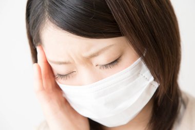 Soluk maskeli hasta bir Asyalı kadının portresi beyaza izole edilmiş.