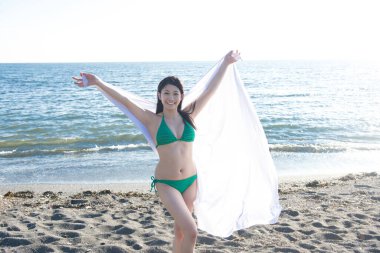 Deniz kenarında poz veren mutlu Asyalı kadın.