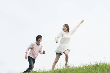 Mutlu genç Asyalı çift yaz parkında koşuyor