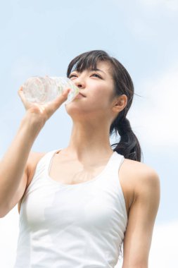 Yaz parkında koşu yaparken su içen güzel Japon kadın. 