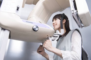 Kadın hasta dişçi tomografisi yapıyor. Dişlerinin röntgenini çeken kadın ortodontik röntgen makinesinin yardımıyla klinikte.