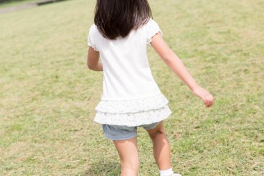 Parkta oynayan Asyalı kızın arkadan görünüşü