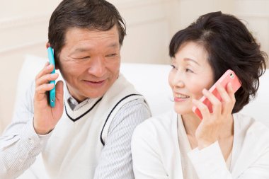 Yetişkin Asyalı çifti telefonları kullanarak kapatın.