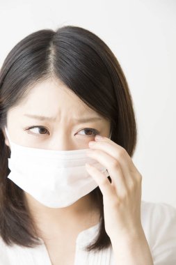 Soluk maskeli hasta bir Asyalı kadının portresi beyaza izole edilmiş.