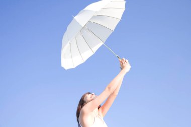 Güzel Asyalı kadın deniz kenarında şemsiyeyle poz veriyor.