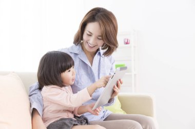 Anne ve kızı akıllı tabletle oynuyorlar.