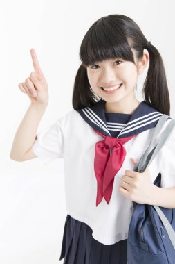 Okul üniformalı güzel bir öğrencinin portresi beyaz arkaplanı işaret ediyor.