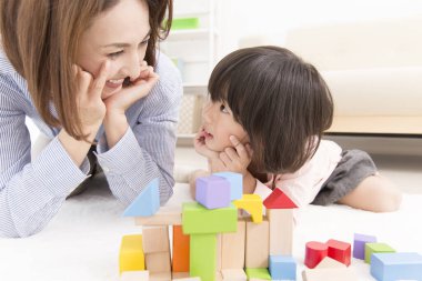 Asyalı anne ve küçük kızı birlikte oynuyorlar.