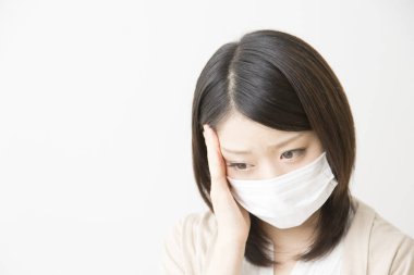 Soluk maskeli hasta bir Asyalı kadının portresi beyaza izole edilmiş.