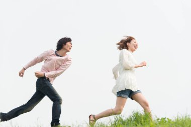 Mutlu genç Asyalı çift yaz parkında koşuyor