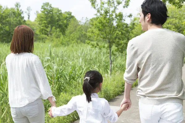 Mutlu Asyalı anne, baba ve kız parkta birlikte vakit geçiriyorlar.