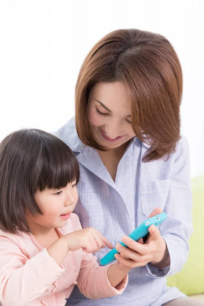 Evde cep telefonu olan Asyalı bir anne ve kız.