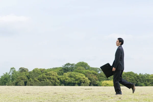 asian businessman walking in the field