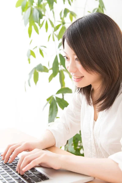 Evde dizüstü bilgisayarda çalışan Asyalı kadın.