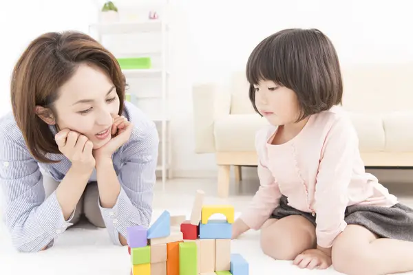 Asyalı anne ve küçük kızı birlikte oynuyorlar.