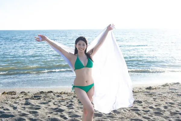 Deniz kenarında poz veren mutlu Asyalı kadın.