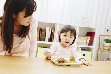 Annesi evde Japon yemeği yiyen tatlı Asyalı kız.