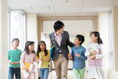 Öğretmenli bir grup Japon çocuk okul koridorunda yürüyor. 