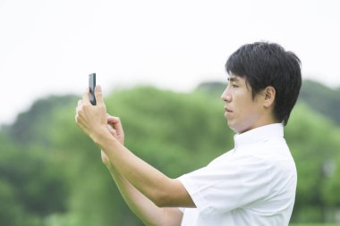 Genç Asyalı adam cep telefonu kullanıyor.