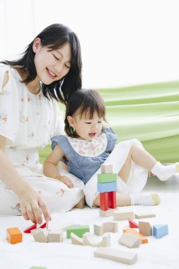 Evdeki oturma odasında annesiyle oynayan tatlı Asyalı küçük kız.