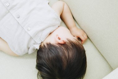 Küçük Asyalı çocuk kanepede uyuyor. 