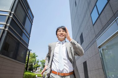 Yakışıklı profesyonel Japon iş adamı sokakta koşuyor.     
