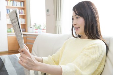 Evde gazete okuyan güzel Asyalı kadının portresi.