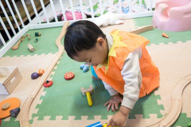 Küçük çocuk içeride ahşap trenle oynuyor.